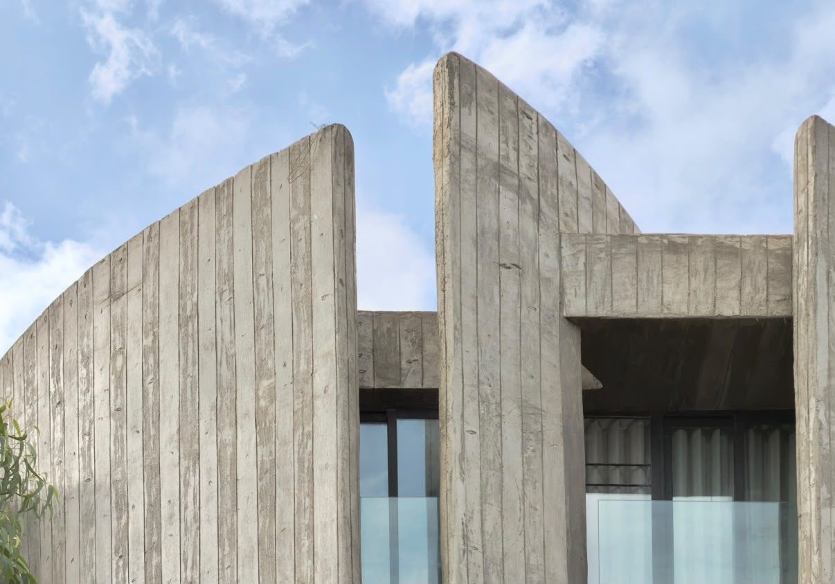 Façade en béton brut à courbes verticales conçue par le cabinet