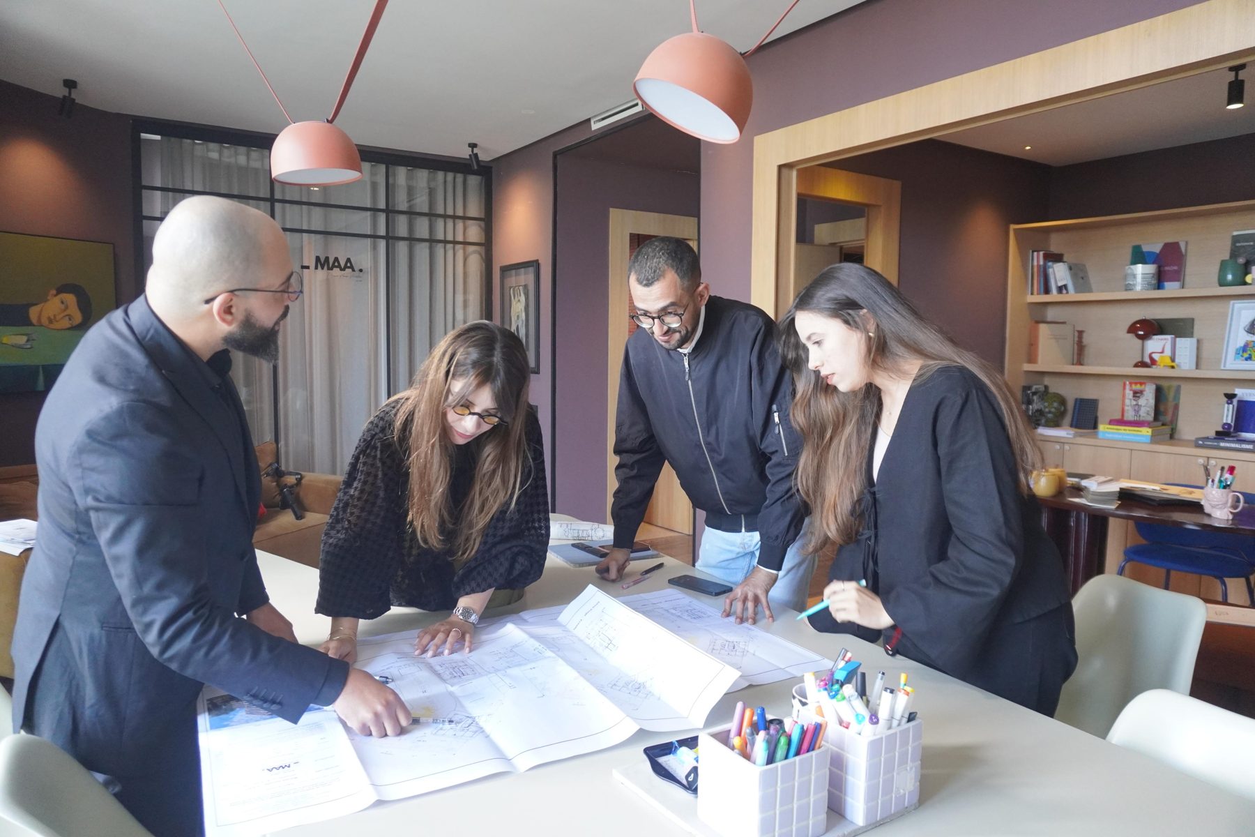 Quatre membres du cabinet réunis autour de plans